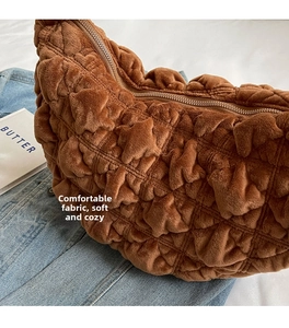 Close-up of brown plush crescent bag featuring textured rhombic pattern and zipper detail
