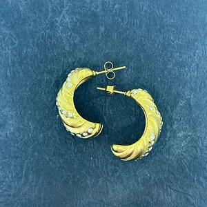 Close-up of vintage 18k gold C-shaped twisted earrings with sparkling inlaid diamonds