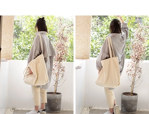 Outdoor lifestyle shot of a large beige canvas tote bag worn by a model in a courtyard