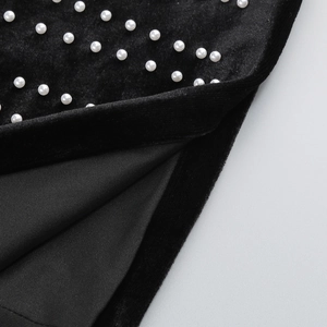 Détail de perles blanches sur tissu en velours noir avec une doublure en maille