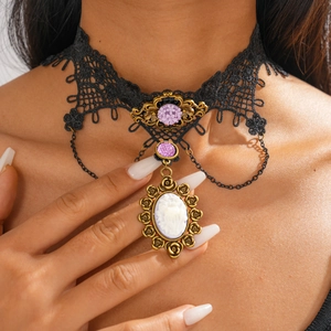 Detail eines Gothic-Spitzenhalsbands mit lila Blume und Vintage-Cameo-Anhänger-Charm