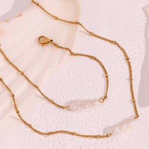 Close-up of 18K gold plated necklace with baroque pearls on a shell background