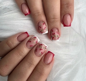 Close-up of square press-on nails with red French tips and cute cherry patterns