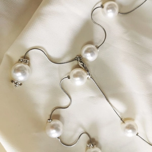 Elegant pearl waist chain with silver snake bone links and crystal accents on silk fabric