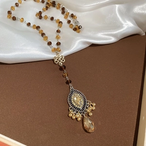 Macro detail of vintage beaded necklace with Chinese knot element and amber teardrop pendant