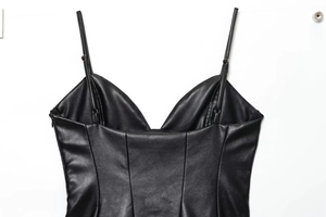 Dettaglio di un mini abito nero in similpelle con spalline sottili e zip invisibile