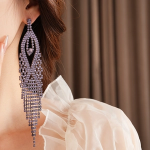 Macro shot of purple rhinestone long tassel earrings worn by a model in a luxury style