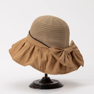 Close-up of caramel sun hat featuring hollow weave top and large decorative bow detail