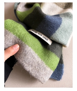 Detail shot of a striped mohair scarf with a white logo tag and soft knit texture