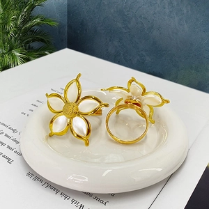 Macro detail of white painted flower napkin rings with gold rim in a ceramic dish
