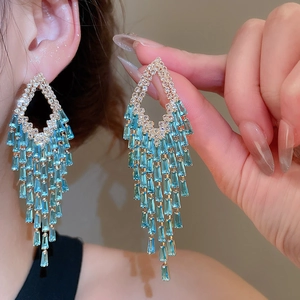 Detail of silver pin tassel earrings with blue rectangular zircons and gold plating