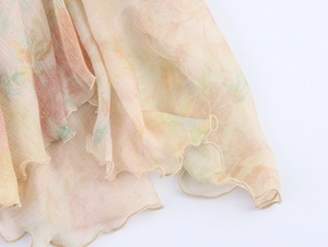 Detail of floral chiffon fabric with ruffled edges in soft orange and green tones