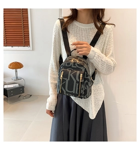 Fashionable black women backpack with letter patterns and metallic zipper detail on model