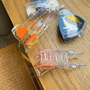 Close-up of translucent acetate goldfish and whale hair claws on a wooden table