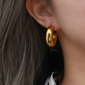 Close-up of a woman wearing a thick chunky hollow 18K gold plated stainless steel hoop earring