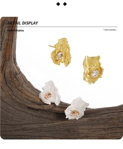 Detail view of asymmetric silver earrings with bark texture and oval-cut zircon stone