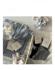Détail de chaussettes mi-mollet en coton avec breloques cloches et nœuds argentés