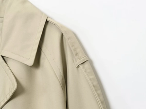 Detailed close-up of khaki trench coat collar and shoulder straps with precise stitching