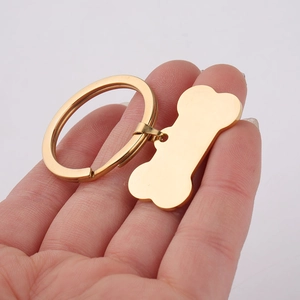Polished gold bone-shaped stainless steel pet tag held by hand for detail