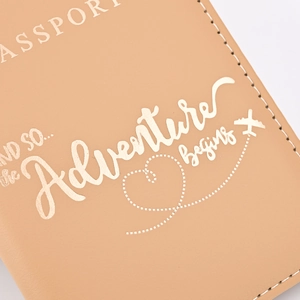 Close-up of brown PU leather passport cover with gold-stamped 'Adventure begins' text