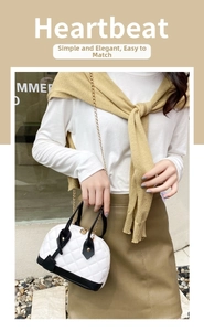 Detail of a quilted crossbody bag with gold chain strap shown on a street model