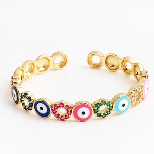 Detail of gold open bracelet featuring colorful evil eye enamel and zircon stones