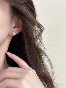 Close-up of pink mermaid pearl stud earrings with iridescent glow on model ear