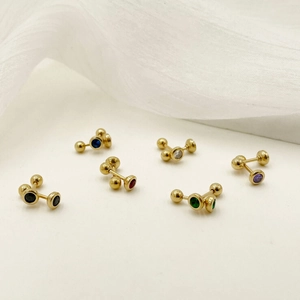 Golden barbell earrings with multi-colored cubic zirconia stones on white fabric