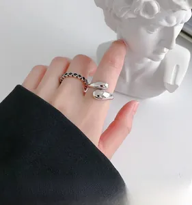 Detail of silver water-drop open ring and black zircon band on a model hand