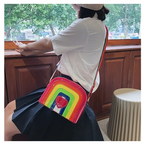 Detailed close-up of rainbow striped semi-circle crossbody bag with red heart