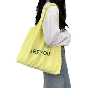 Minimalist canvas tote bag in light yellow with green AREYOU lettering on white background