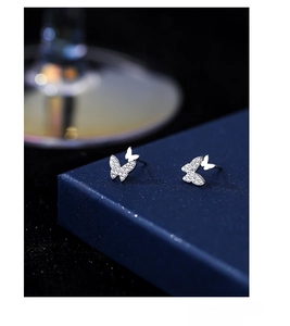 Macro detail of S999 sterling silver butterfly studs with sparkling crystal accents