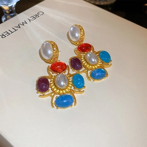 Détail de boucles d'oreilles baroques vintage avec perles et gemmes sur un livre blanc