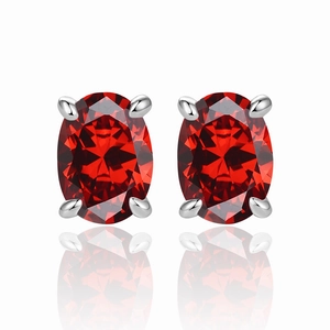 Macro shot of oval cut ruby red gemstone earrings in four-prong silver setting