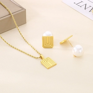Detail of gold geometric square jewelry set with white pearls and twisted rope chain