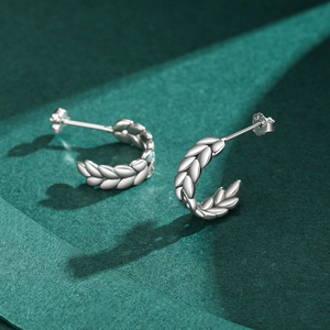 Vintage S925 sterling silver leaf stud earrings with metallic luster on green background