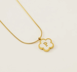 Detailed macro view of 18K gold clover pendant with letter P on white shell inlay