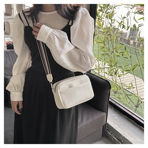 Detail of white lychee-patterned PU leather square bag with colorful striped wide strap
