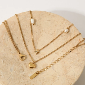 Gold layered stainless steel necklace with star and heart charms on marble tray