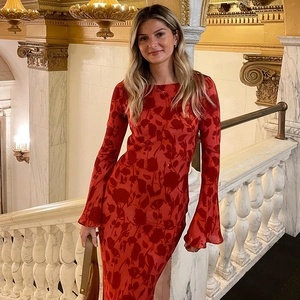 Detail of bohemian red floral maxi dress with bell sleeves on elegant marble stairs