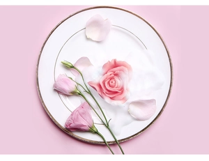 Gros plan d'un savon rose en forme de rose avec mousse onctueuse sur une assiette dorée