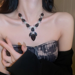 Close-up of luxury silver necklace with black teardrop pendant and pink crystals