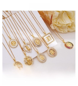 Close-up of 18k gold plated Virgin Mary pendants in heart and oval shapes with zircon stones