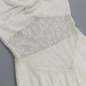 Detailed close-up of white floral lace crochet and sheer mesh stitching on the dress