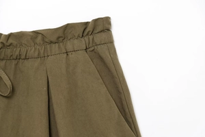 Detail of olive green elastic waistband with pleated texture and functional side pockets