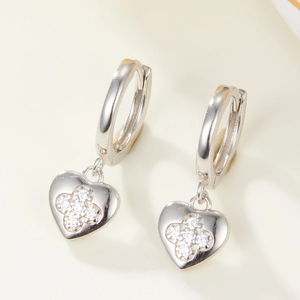 Macro detail of silver heart earrings with clover-shaped cubic zirconia inlay