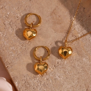 Detailed close-up of golden heart jewelry set with polished earrings and necklace