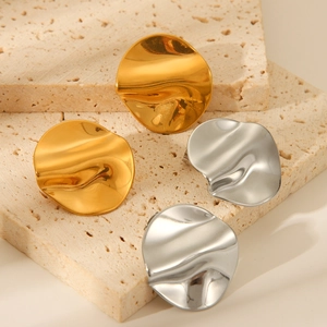 Irregular wavy disc earrings in gold and silver finish on textured stone background