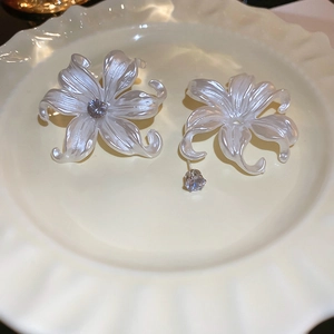 Macro detail of acrylic flower earring with pearl finish and sparkling zircon center