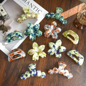 Detailed flat lay of colorful marble acetate flower hair claws on a wooden table